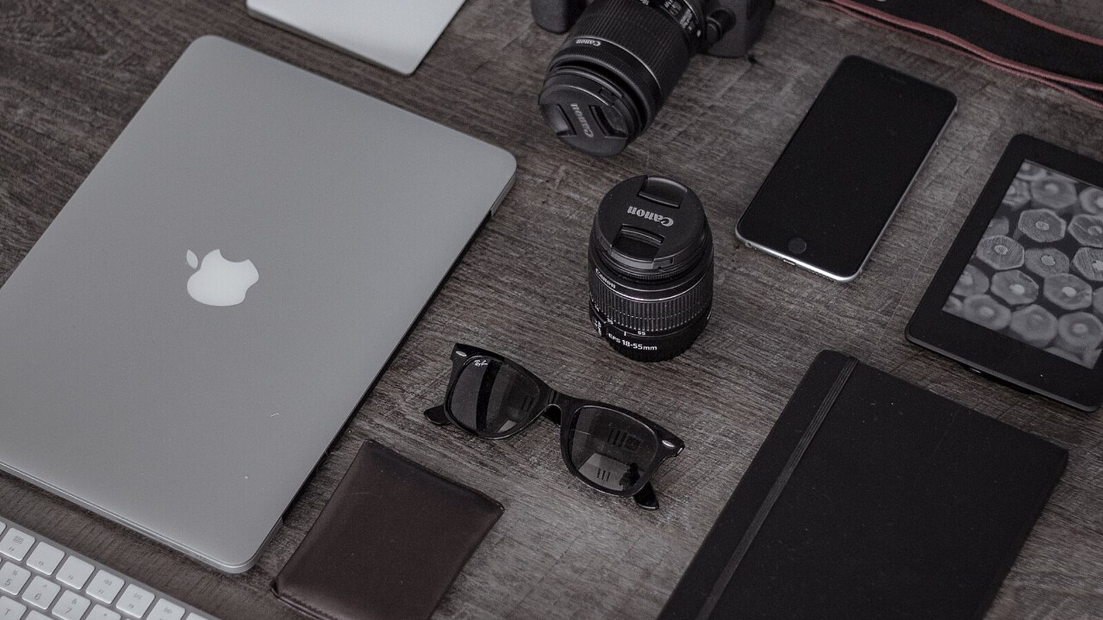 Laptop beside a phone camera and notebook on a desk